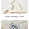 Beige Canvas Tasche mit hellbraunen Riemen und gesticktem Markenlogo auf der Seite.