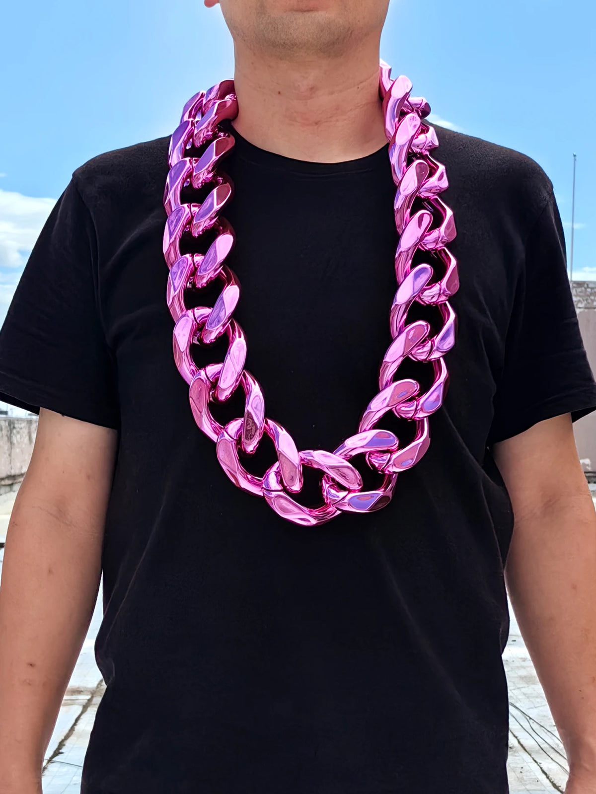 A man wearing a chunky pink acrylic Cuban link necklace around his neck.