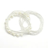 A delicate white bead chain for body jewelry, featuring small pearls and thin wire strands.
