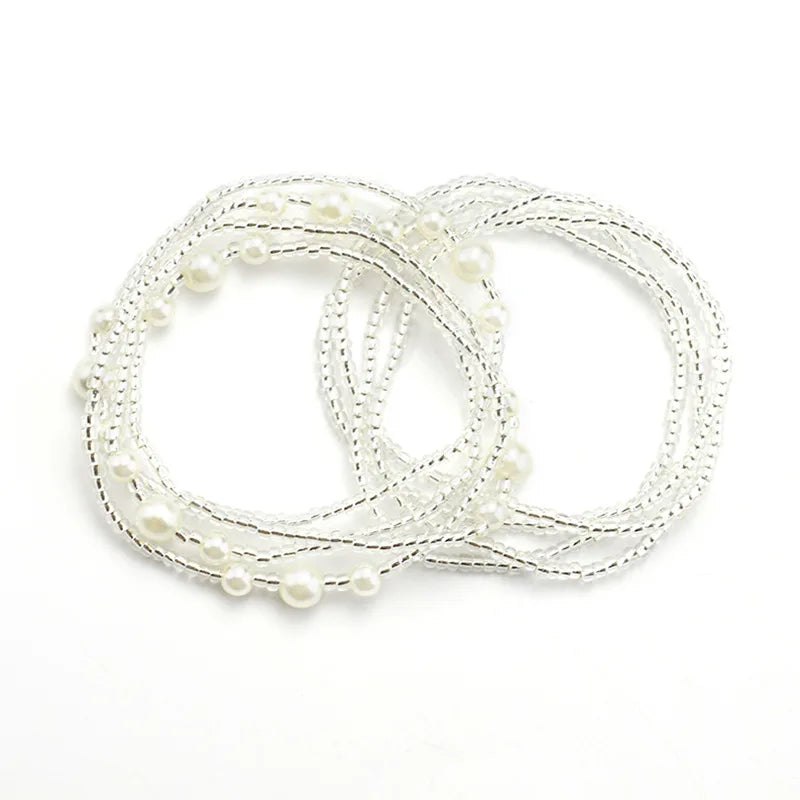 A delicate white bead chain for body jewelry, featuring small pearls and thin wire strands.