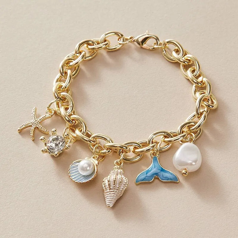 Gold chain bracelet featuring an ocean pearl charm, starfish, and shell accents.