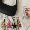 Collection de porte-clés à ballons Y2K esthétiques et une pochette noire, présentées sur un tissu blanc.