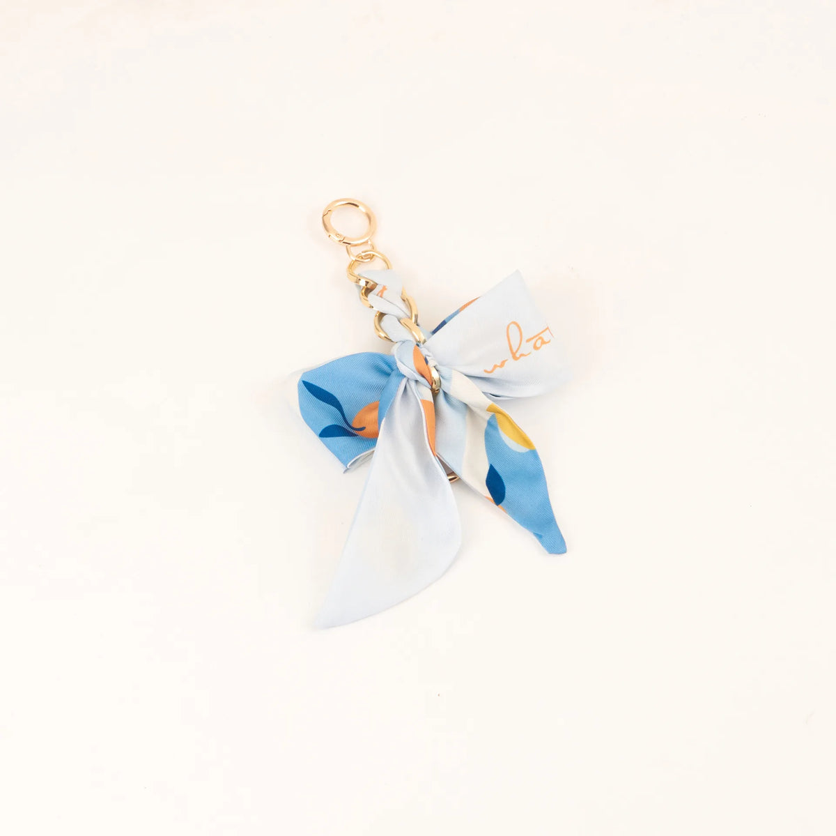 Lazo de cinta de seda azul claro atado en un nudo con un anillo de llavero de color dorado.