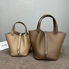 A tan genuine leather bucket bag with a zipper closure is displayed on a gray surface.