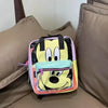 A yellow and black cow print fashion backpack resting on a brown sofa cushion.