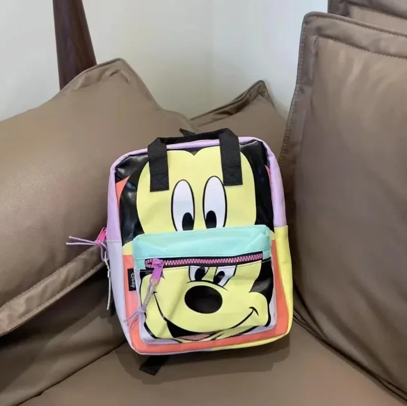 A yellow and black cow print fashion backpack resting on a brown sofa cushion.