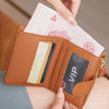 A hand is opening a brown PU leather bifold wallet with a zipper closure, revealing cards and cash.