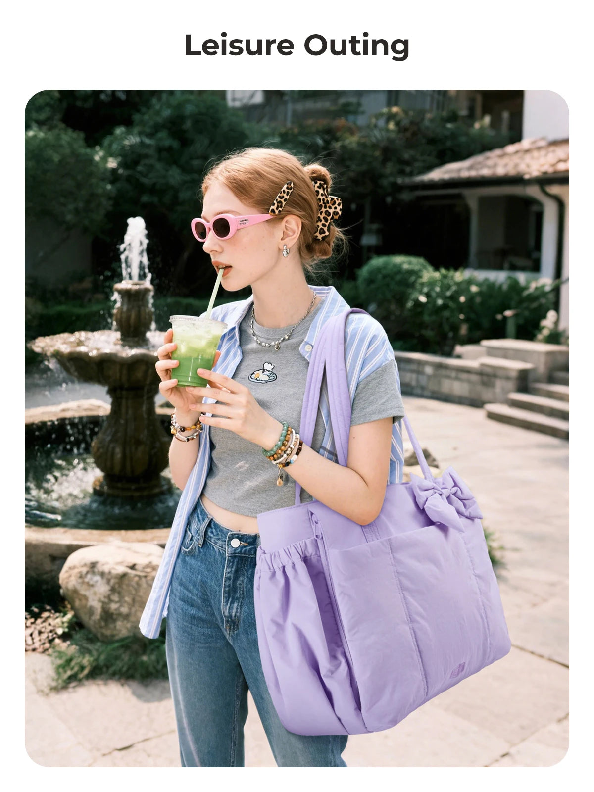 A woman wearing sunglasses and a striped shirt holds a purple tote bag outdoors.