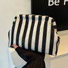 A black and white striped summer crochet handbag is displayed against a dark background.