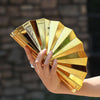 A hand holds a gold acrylic chain crossbody bag with multiple layered, reflective panels.