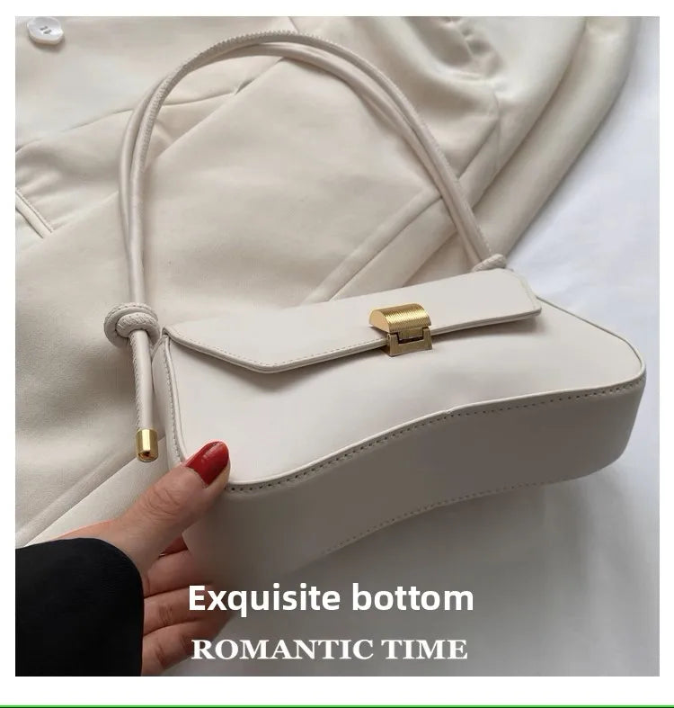 A light beige leather crossbody bag with gold hardware shown being held by a hand.