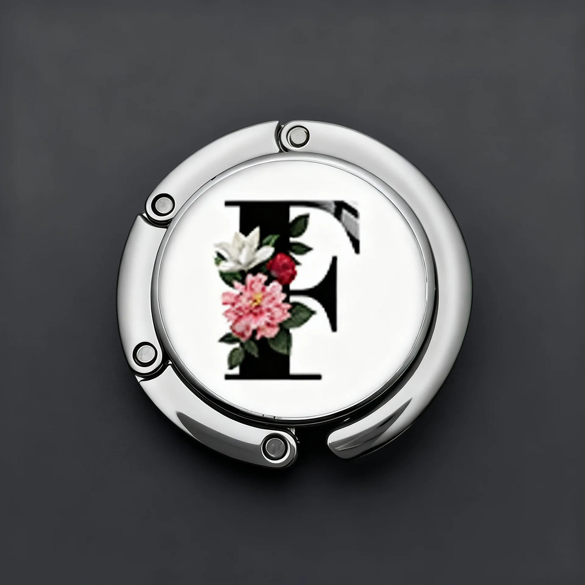 Silver foldable letter H hanger hook with floral accents against a dark gray background