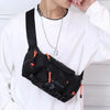 Eine Person trägt einen weißen Pullover und hält eine schwarze taktische Brusttasche mit orangefarbenen Akzenten und einer si