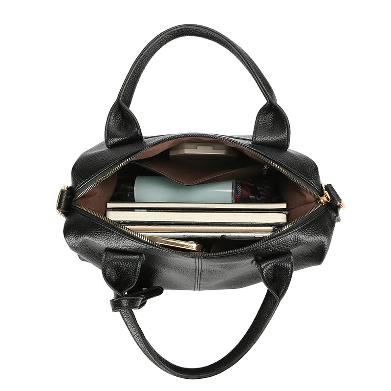 A black soft leather tote bag with a top handle and adjustable strap, showing the interior compartment.
