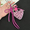 A pink and black leopard print plush heart pendant keychain with pink string and pearl accents.
