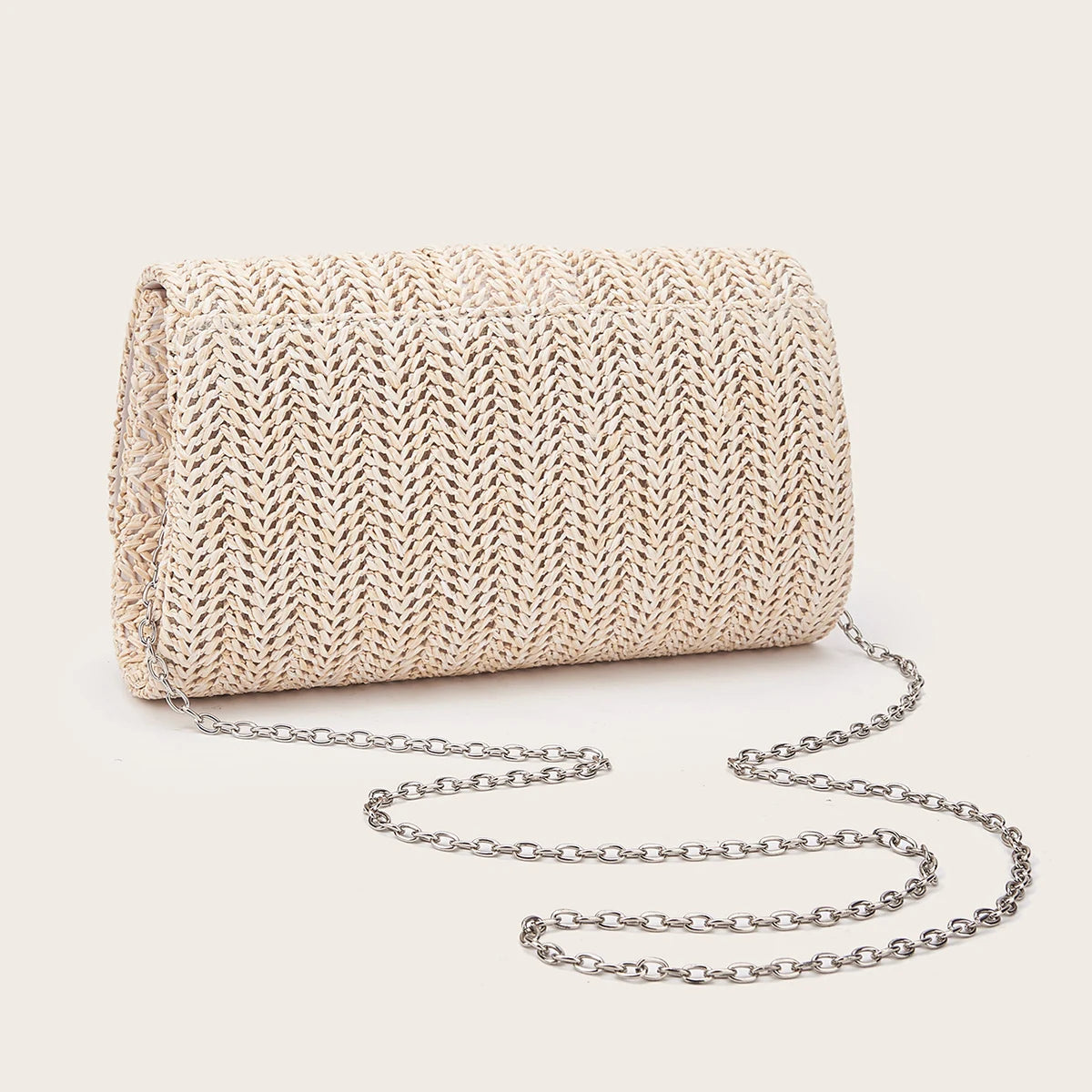 A woven straw envelope clutch with a silver chain strap resting on a light background.