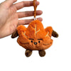 An orange maple leaf plush charm hanging from a gold-colored keychain ring.