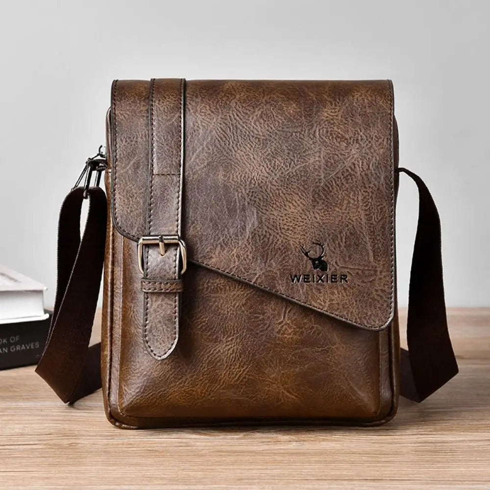 A brown PU leather messenger bag with a leather strap is shown on a wooden surface.