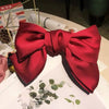 A vibrant red silk bow hair clip displayed on a white surface.