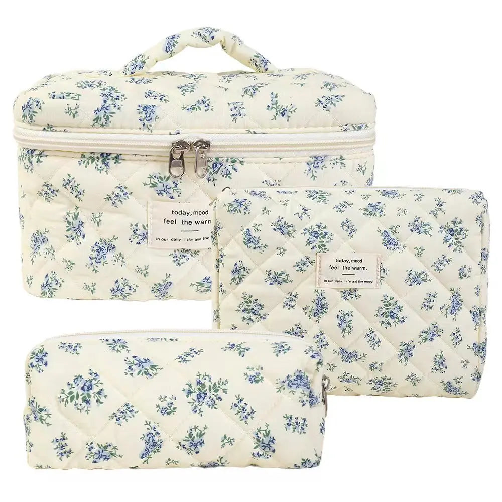 A set of three quilted cotton makeup organizers featuring a white background with blue floral patterns.
