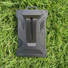 A black slim aluminum metal ID card wallet lying on green grass.