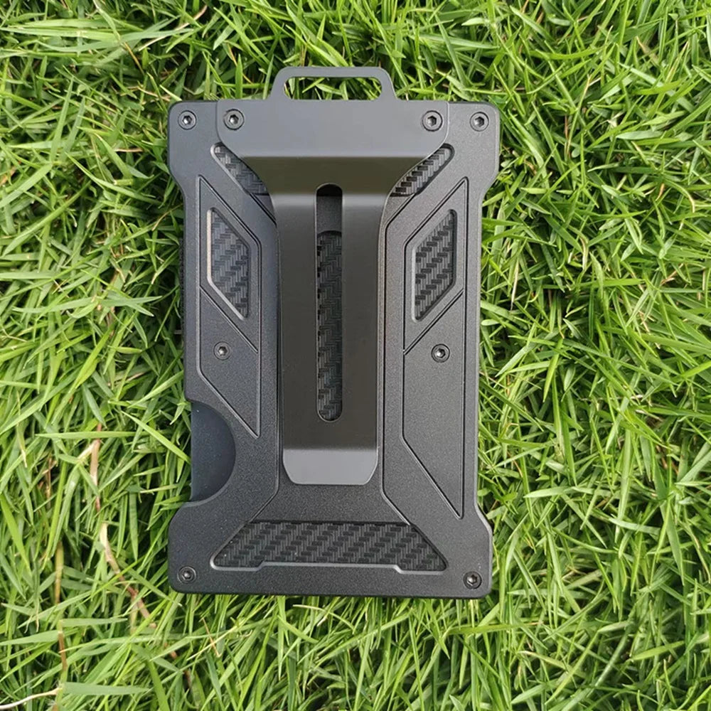 A black slim aluminum metal ID card wallet lying on green grass.