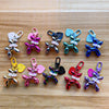 A collection of colorful balloon dog keychain charms in various colors and styles arranged on a wooden surface.