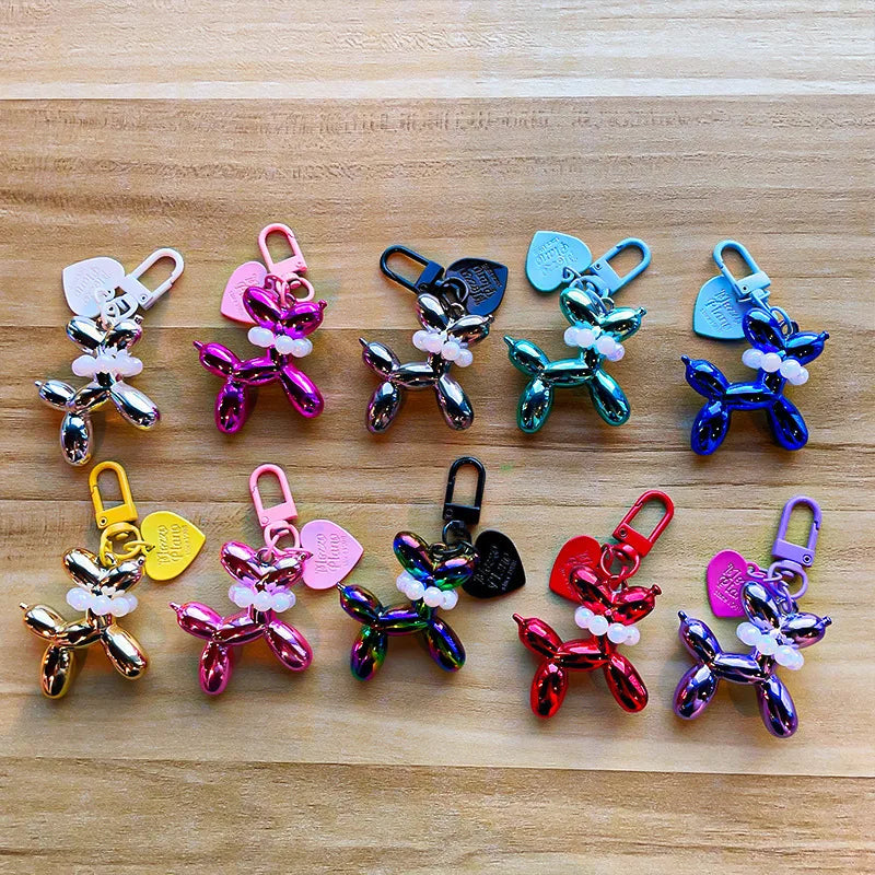 A collection of colorful balloon dog keychain charms in various colors and styles arranged on a wooden surface.