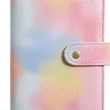 A pink and white gradient leather notebook with a gold-colored closure.