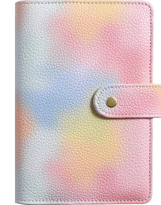 A pink and white gradient leather notebook with a gold-colored closure.