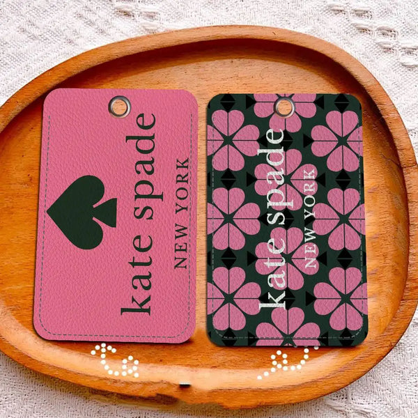 Porta tarjetas de cuero rosa con diseño de trébol y un porta tarjetas estampado en verde oscuro sobre una tabla de madera.