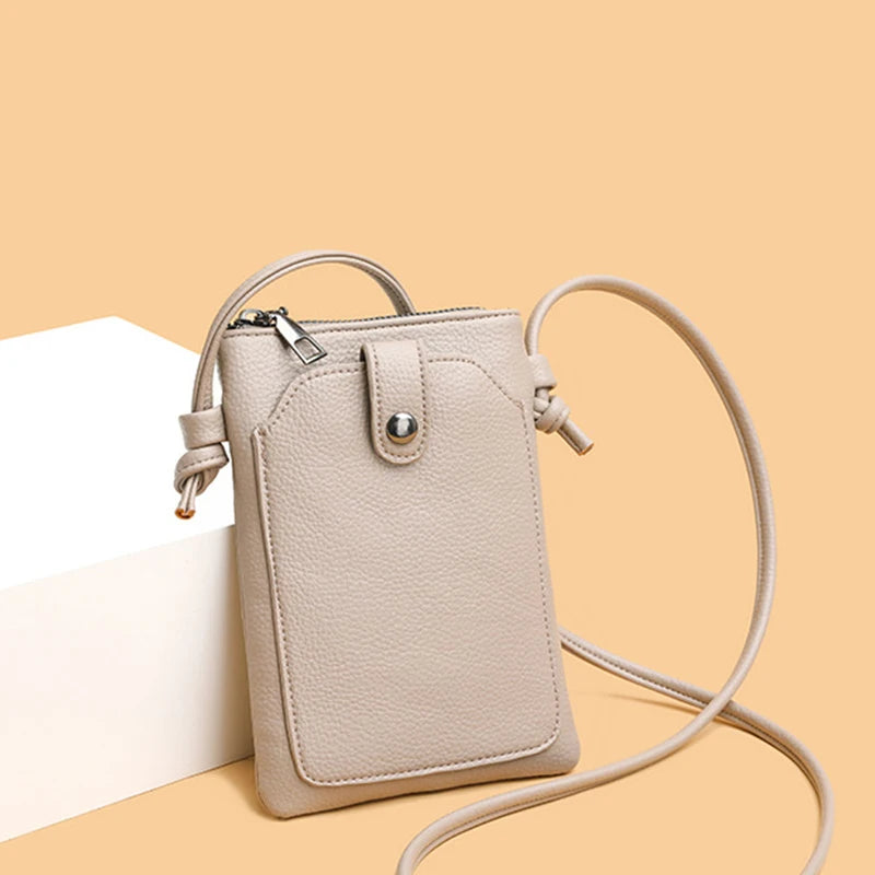 A beige compact PU leather crossbody bag with a zipper closure and a long strap is shown against a light background.
