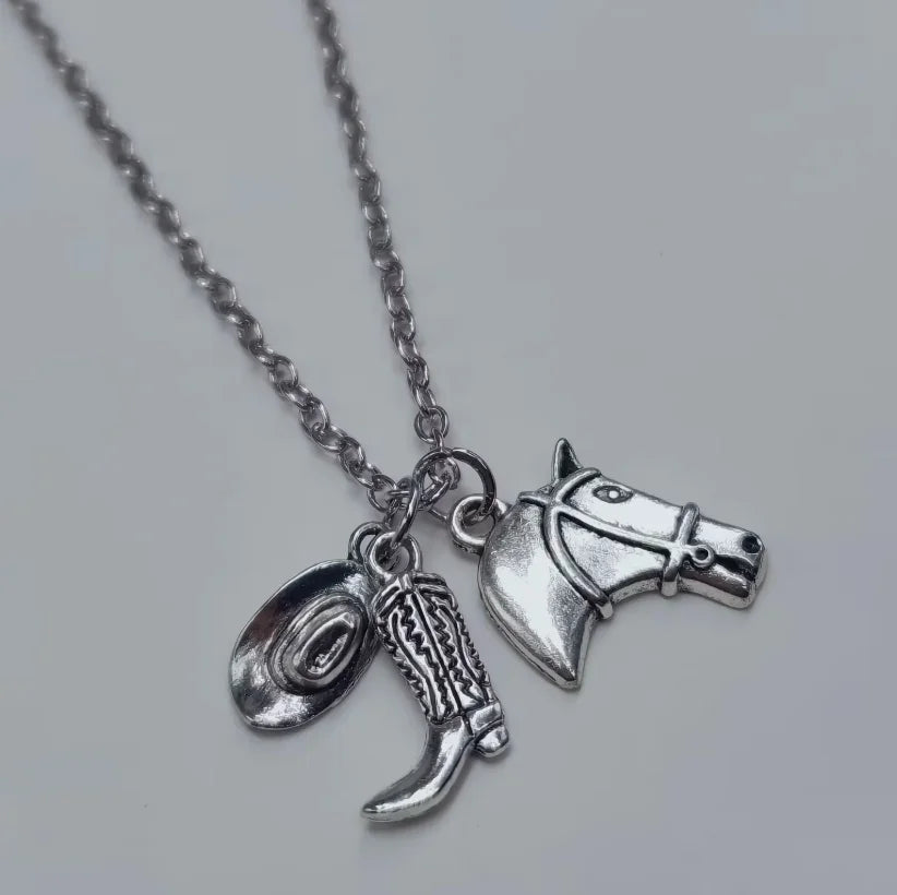 Silver necklace with a cowboy boot, hat, and horseshoe keychain set.