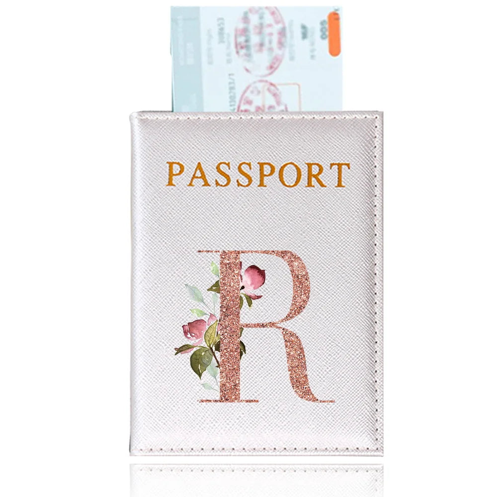 A light pink leather passport holder featuring a gold embossed letter R and floral accents.