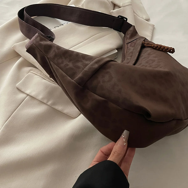 Dunkelbraune Leopardenmuster-Crossbodytasche liegt auf einem weißen Blazer.
