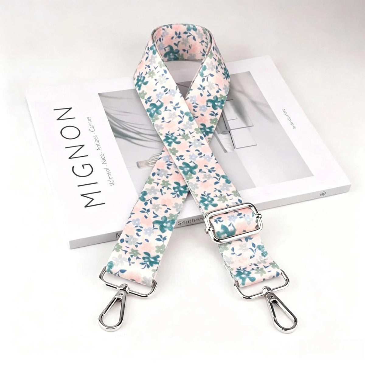 A floral patterned nylon crossbody bag strap with a silver metal buckle displayed on a white box.