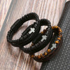 A stack of black leather bracelets featuring tiger eye beads resting on a dark surface.
