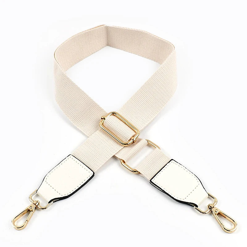A beige canvas cotton bag strap with gold-toned metal hooks shown in an X-shape.