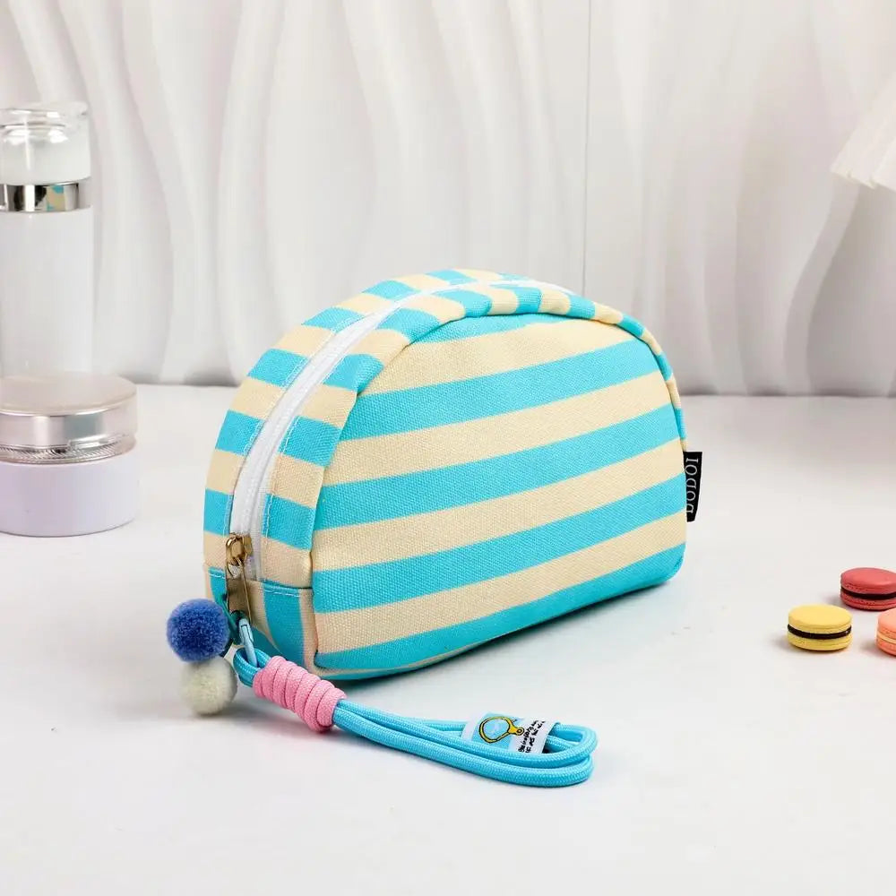 Pochette en crochet rayée tissée bleu clair et crème avec un cordon rose attaché.