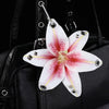 A white and pink orchid flower keychain attached to a black leather handbag.