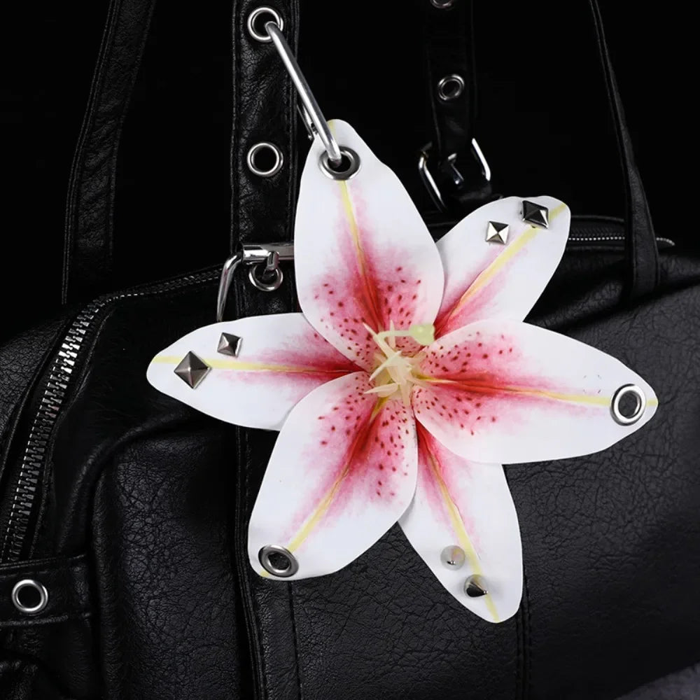 A white and pink orchid flower keychain attached to a black leather handbag.