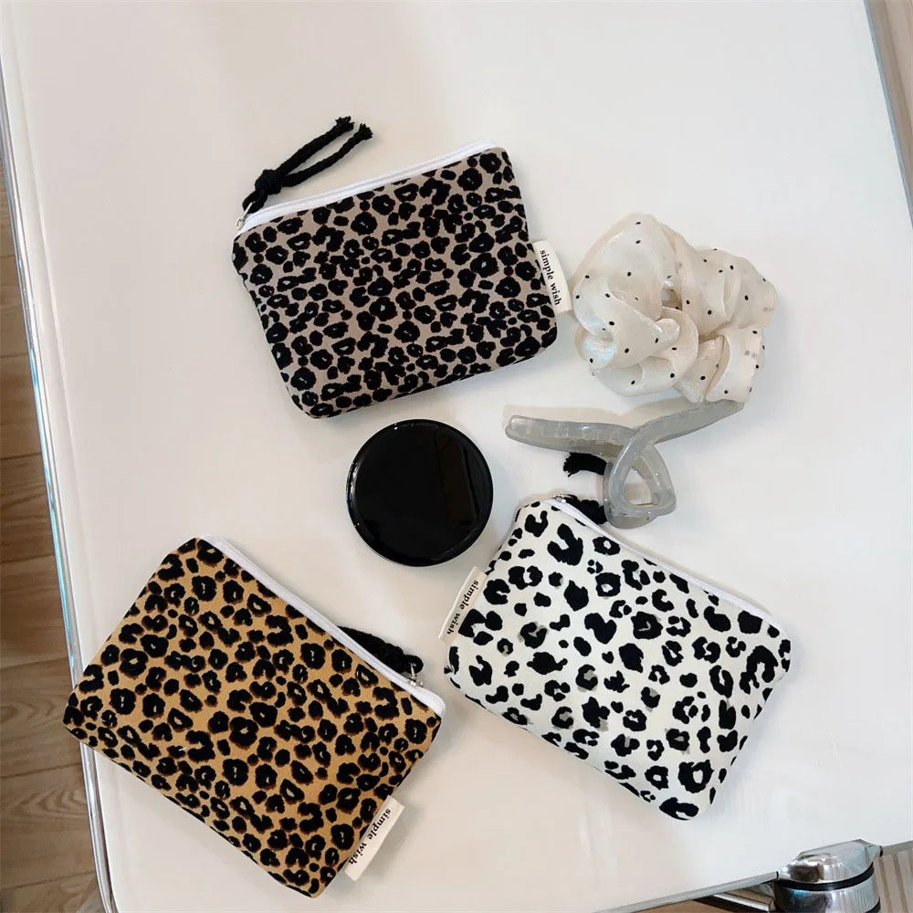 A leopard print cosmetic bag with a black lining and drawstring closure is displayed on a white surface.