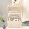 A beige waterproof makeup organizer pouch with clear compartments and a brush inside, held by a person's hand.