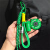 A hand holds a green fitness keychain with a yellow toggle and an oval green fitness tag.