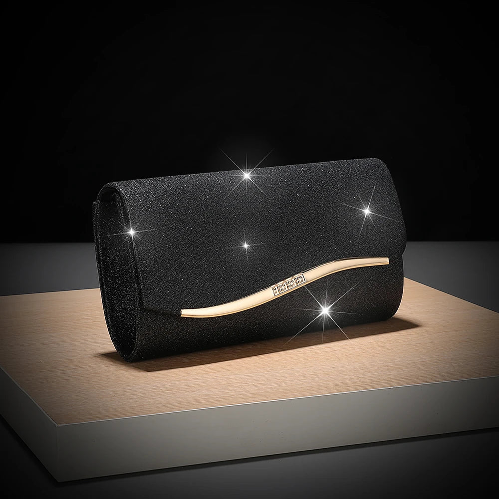 A black sequined envelope clutch with a gold-toned leather strap is displayed on a wooden surface.