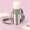 A light gray and white crossbody sling water bottle bag standing upright on a pink surface.