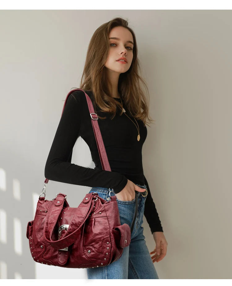 Eine Frau präsentiert eine maroon-Vintage-Leder-Schultertasche mit rosa Träger und dunkler Kleidung.