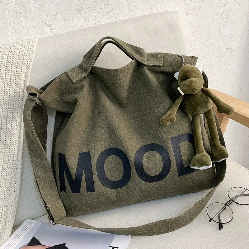 A dark olive green canvas tote bag featuring the word MOOD printed in large, dark letters.