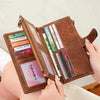 A brown leather trifold clutch wallet is shown open, displaying various cards and documents.