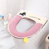 A plush pink waterproof toilet seat cover with a black cat design is shown on a white toilet.